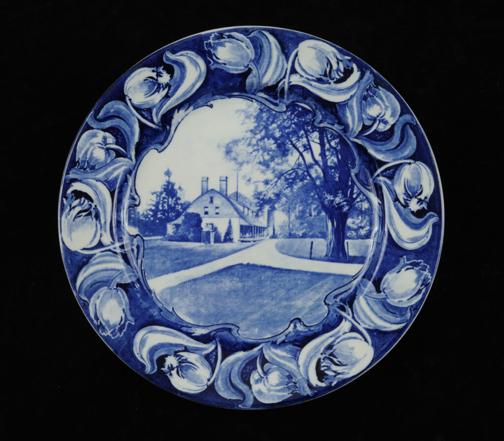 Circular blue-and-white ceramic plate with Mount Gulian manor house pictured within a tulip flower border