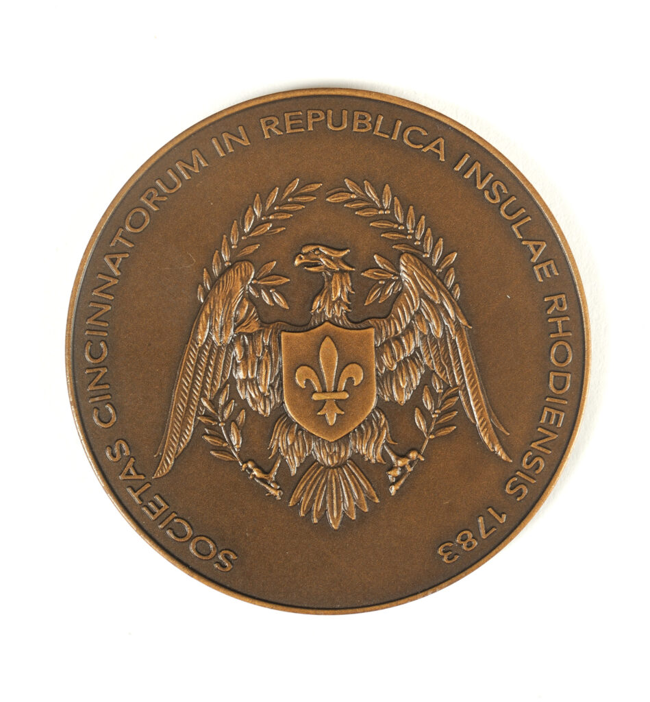 Click for a larger view. Circular bronze medal picturing a bald eagle with a fleur-de-lys on its chest